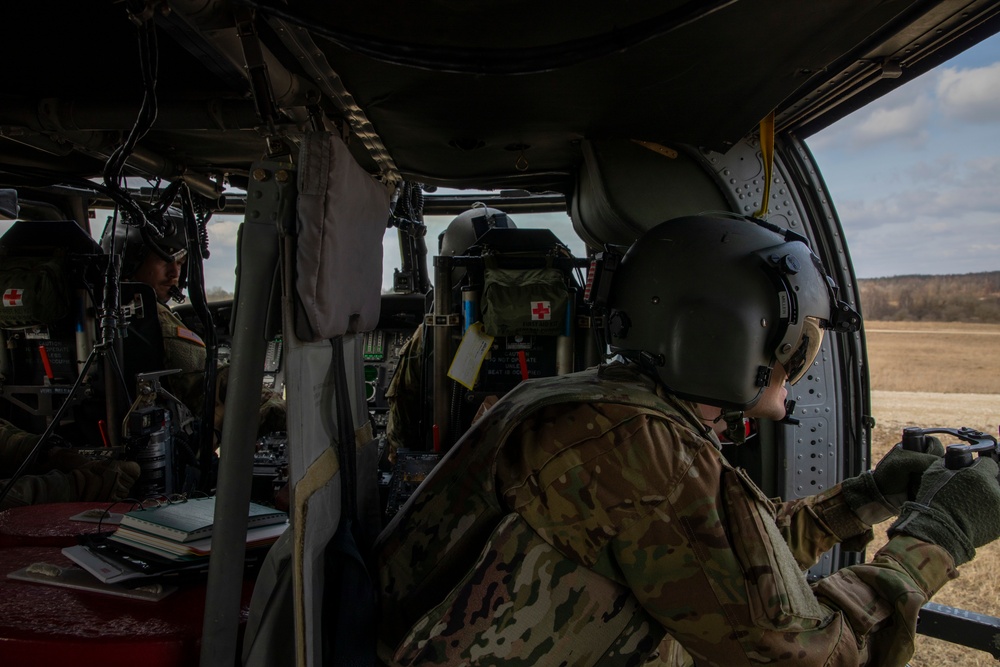 CW2 Ryan Zent observes Cpt. J ared Miller firing an M240H from a UH-60 Blackhawk at Grafenwoehr Training Area, Germany on March 16, 2022