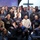 A large group of approximately 20-25 people pose together for a group photo inside what appears to be a church or religious venue. Several individuals are wearing matching black t-shirts with the text 'TAK WIERZE!' (Polish for 'YES I BELIEVE!'). The setting includes a visible cross, a projection screen displaying 'Betania,' and musical equipment, suggesting a religious gathering or youth ministry event.