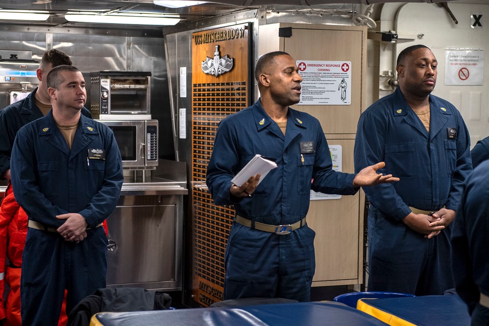 Senior Chief Culinary Specialist Carlos Richardson, middle, from Birmingham, Ala., conducts a liberty brief with Sailors