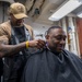 Retail Specialist 3rd Class Alajuwn Nealy-Davis, left, from Houston, Texas, cuts Chief Culinary Specialist Daron Watts’s, right, from Minden, La., hair in the barber shop