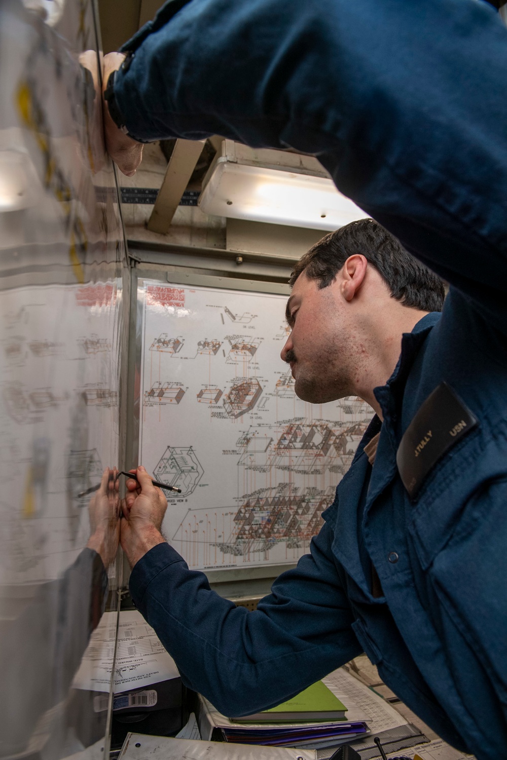 Ensign James Tully, from Long Island, N.Y., marks reported notes on a ship diagram during a firefighting drill