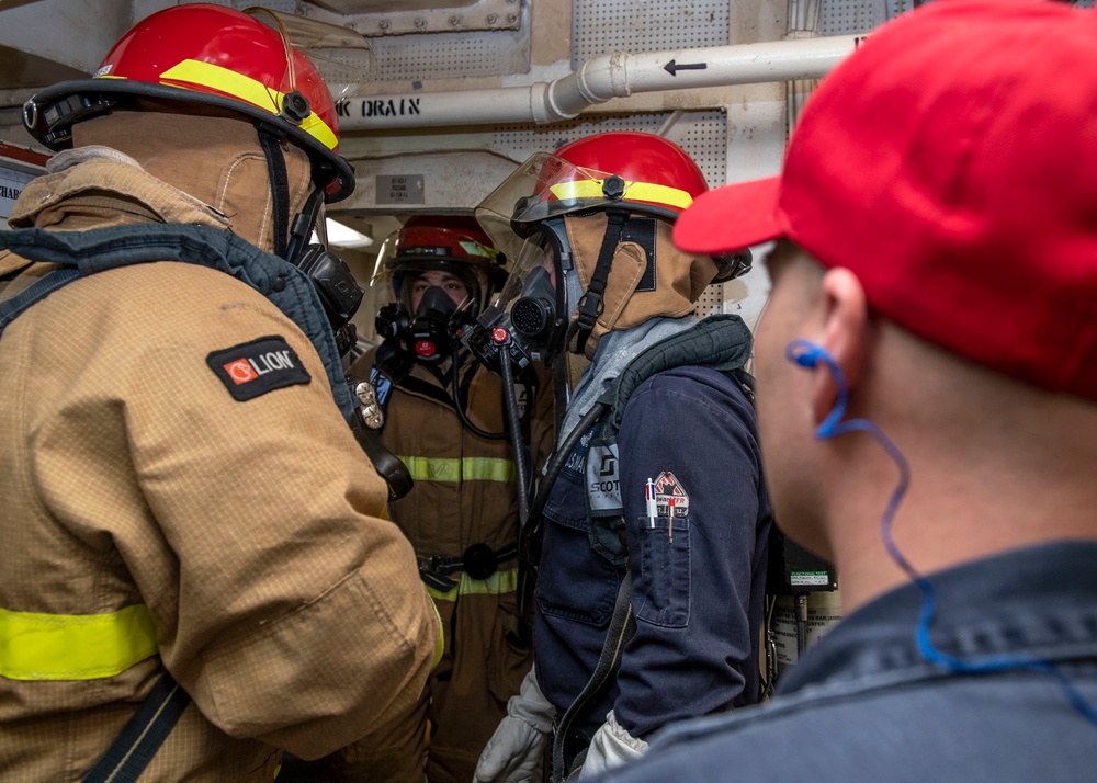 Sailors discuss firefighting procedures with a training team leader Damage Controlman 1st Class Adam Foster, right, from Norfolk, Va., during a firefighting drill