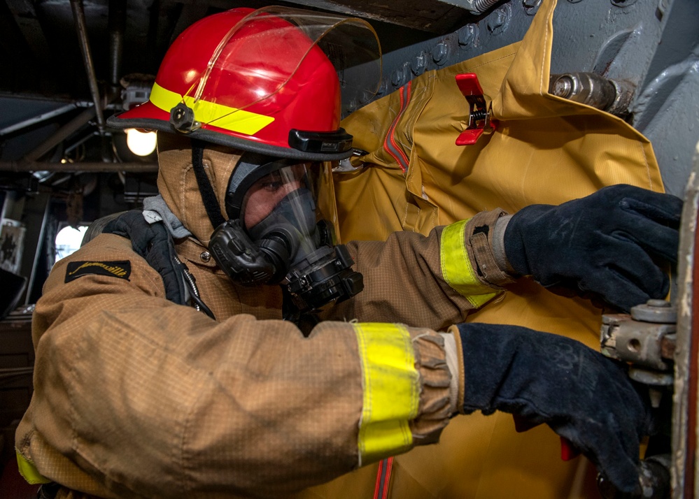 Damage Controlman Fireman Gerardo Vargasarellano, from Oklahoma City, Okla., affixes a smoke curtain to an open hatch during a firefighting drill