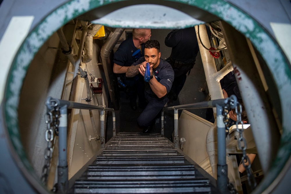 Fire Controlman 2nd Class Dylan Rodriguez, from Menifee, Calif., clears a ladder well, with a training firearm, during an anti-terrorism drill