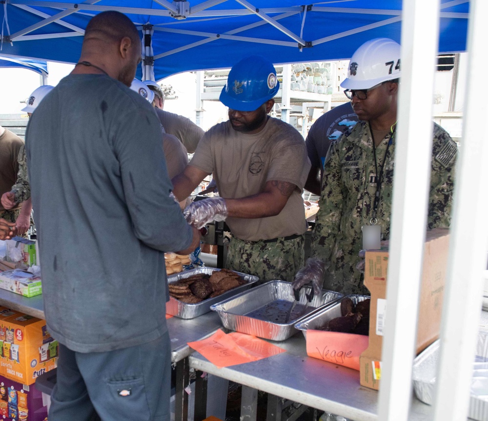 Members of the USS John C. Stennis Mustang Association serve meals to Sailors and Newport News Shipbuilding contractors in a burger burn event aboard the ship.