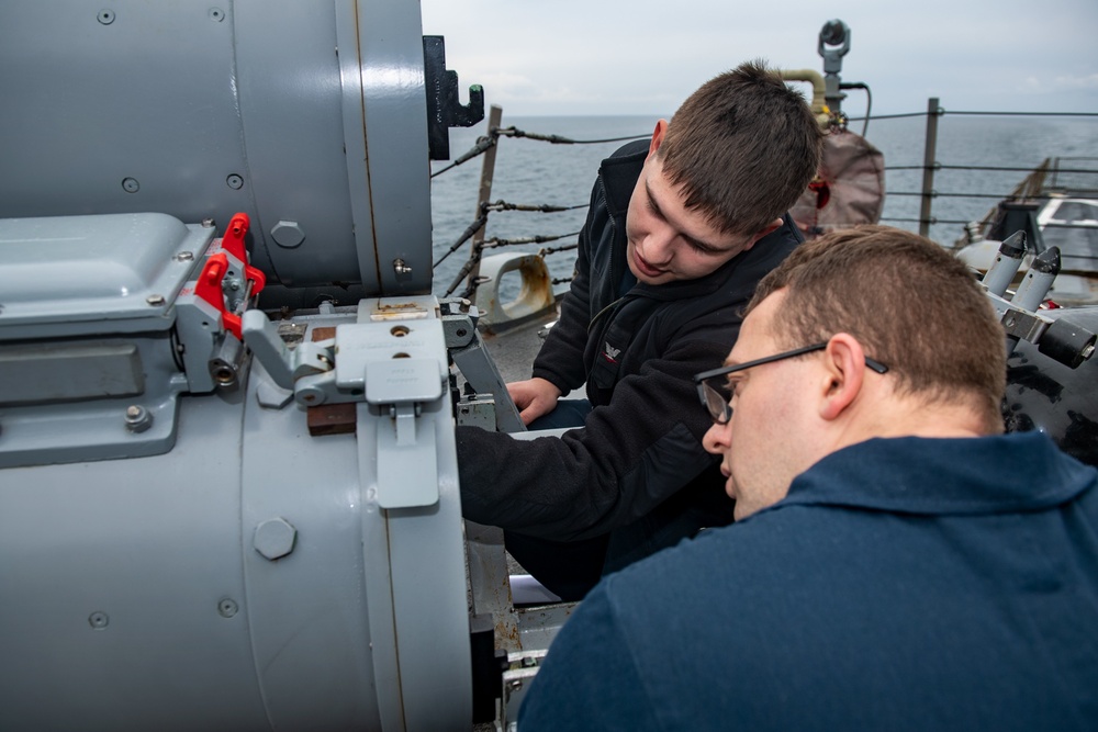 Gunner’s Mate 3rd Class Logan Marrocco, top, from Deer Park, Wash., instructs Sonar Technician (Surface) 3rd Class Joseph Brown, bottom, from Providence, R.I., on Mark-32 surface vessel torpedo tube maintenance