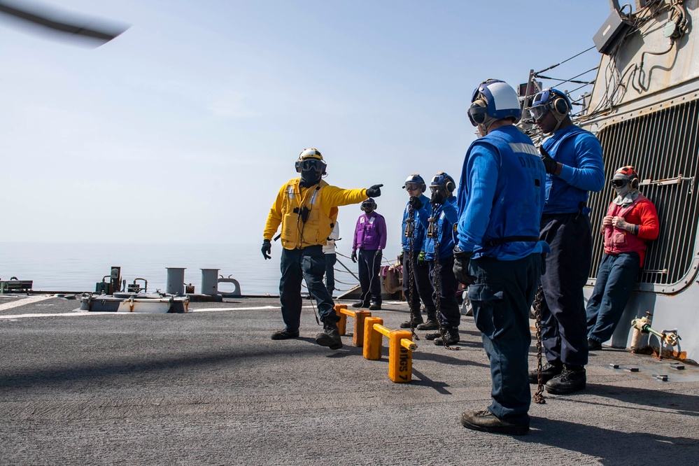 Sailors aboard Arleigh Burke-class guided-missile destroyer USS Mitscher (DDG 57) verify chocks and chains are removed from an MH-60S Sea Hawk helicopter