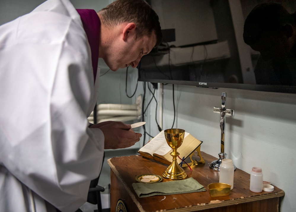 Lt. Fr. Rene Pellessier, from Lafayette, La., assigned to Nimitz-class aircraft carrier USS Dwight D. Eisenhower (CVN 69) prepares for Catholic mass