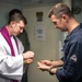 Lt. Fr. Rene Pellessier, left, from Lafayette, La., assigned to Nimitz-class aircraft carrier USS Dwight D. Eisenhower (CVN 69) offers communion to Ensign Matthew Webber, from York, Maine, during a Catholic mass