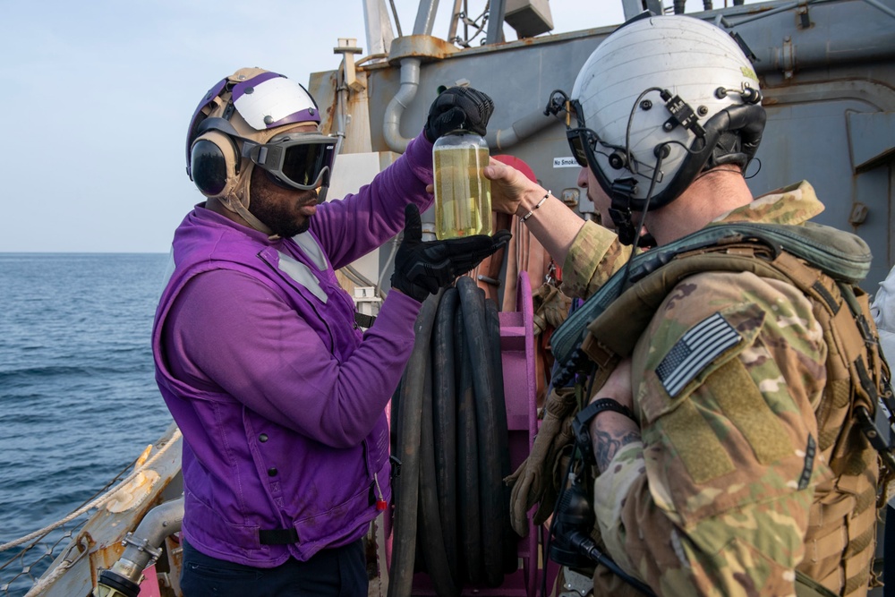 Gas Turbine Systems Technician 3rd Class Demario Spencer, left, from Monroe, La., verifies a fuel sample is clear and bright