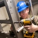 Sailors performs maintenance on ladderwell