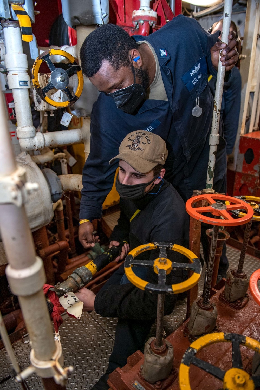 Gas Turbine Systems Technician 3rd Class Demario Spencer, top, from Monroe, La., instructs Fireman Coby Francis, bottom, from Vancouver, Wash., on proper nozzleman techniques during a firefighting drill