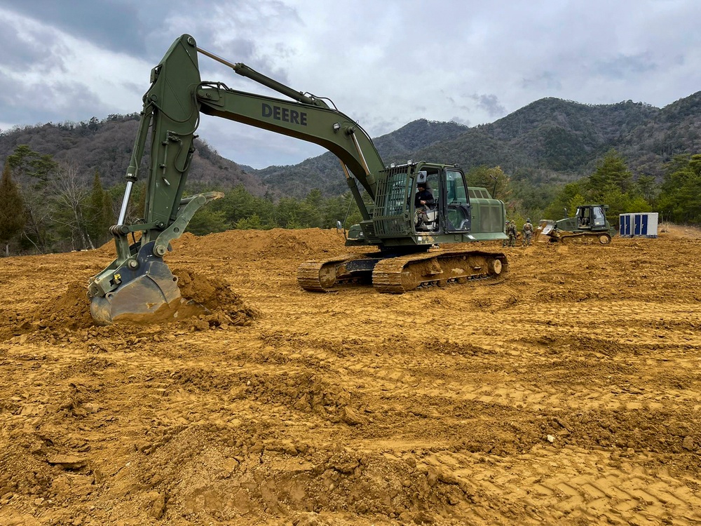 NMCB THREE Seabees operates a John Deere 210G Excavator to create a fighting position in the JLTV Operation Course.