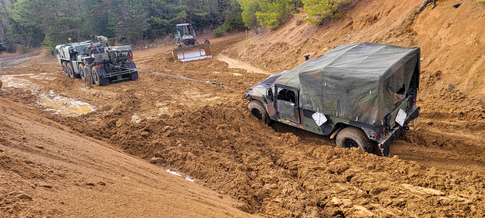 NMCB THREE Seabees utilize a wrecker winch to recover a Humvee stuck in the mud