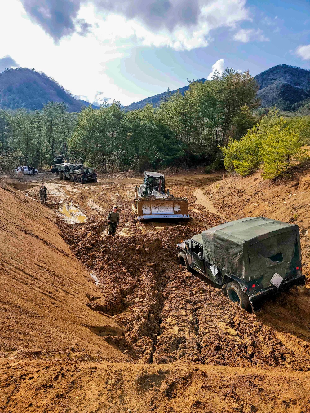 NMCB THREE Seabees utilize bulldozer to remove a Humvee from the mud on board MCAS Iwakuni