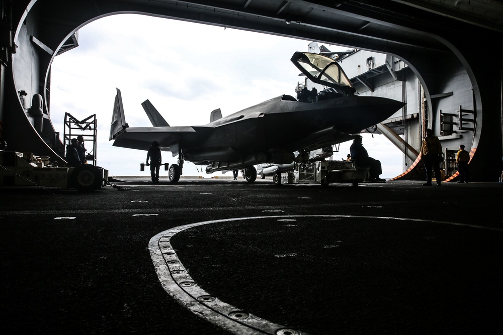 Abraham Lincoln Sailors transport aircraft in the hangar bay