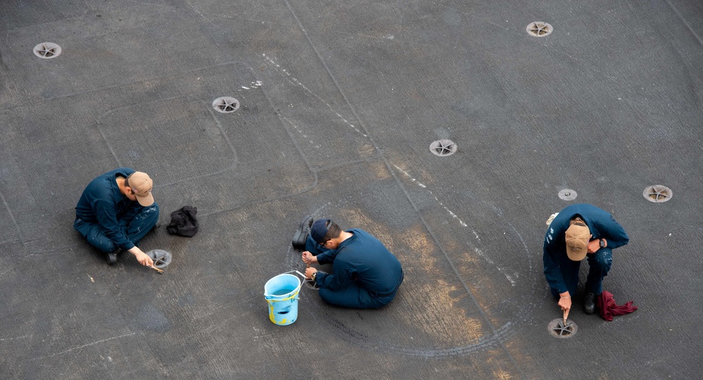 Sailors clean pad-eyes on the flight deck of Nimitz-class aircraft carrier USS Carl Vinson