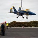 Sailors and civilian personnel transport an F/A-18 super hornet Blue Angel onto the flight deck of Nimitz-class aircraft carrier USS Carl Vinson