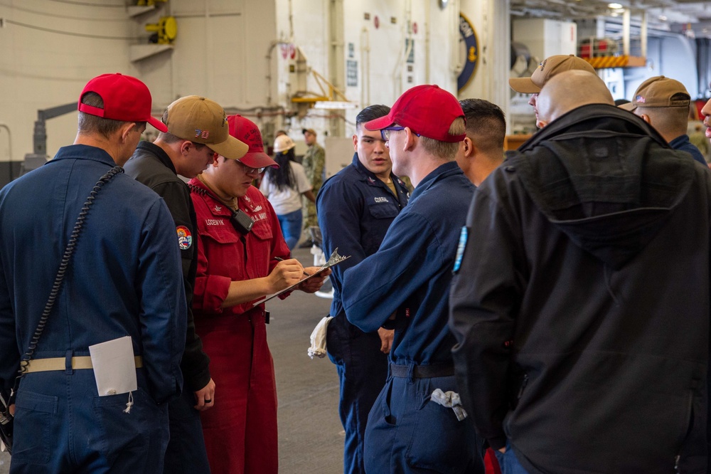 Sailors muster the in-port emergency training team in the hangar bay aboard of Nimitz-class aircraft carrier USS Carl Vinson