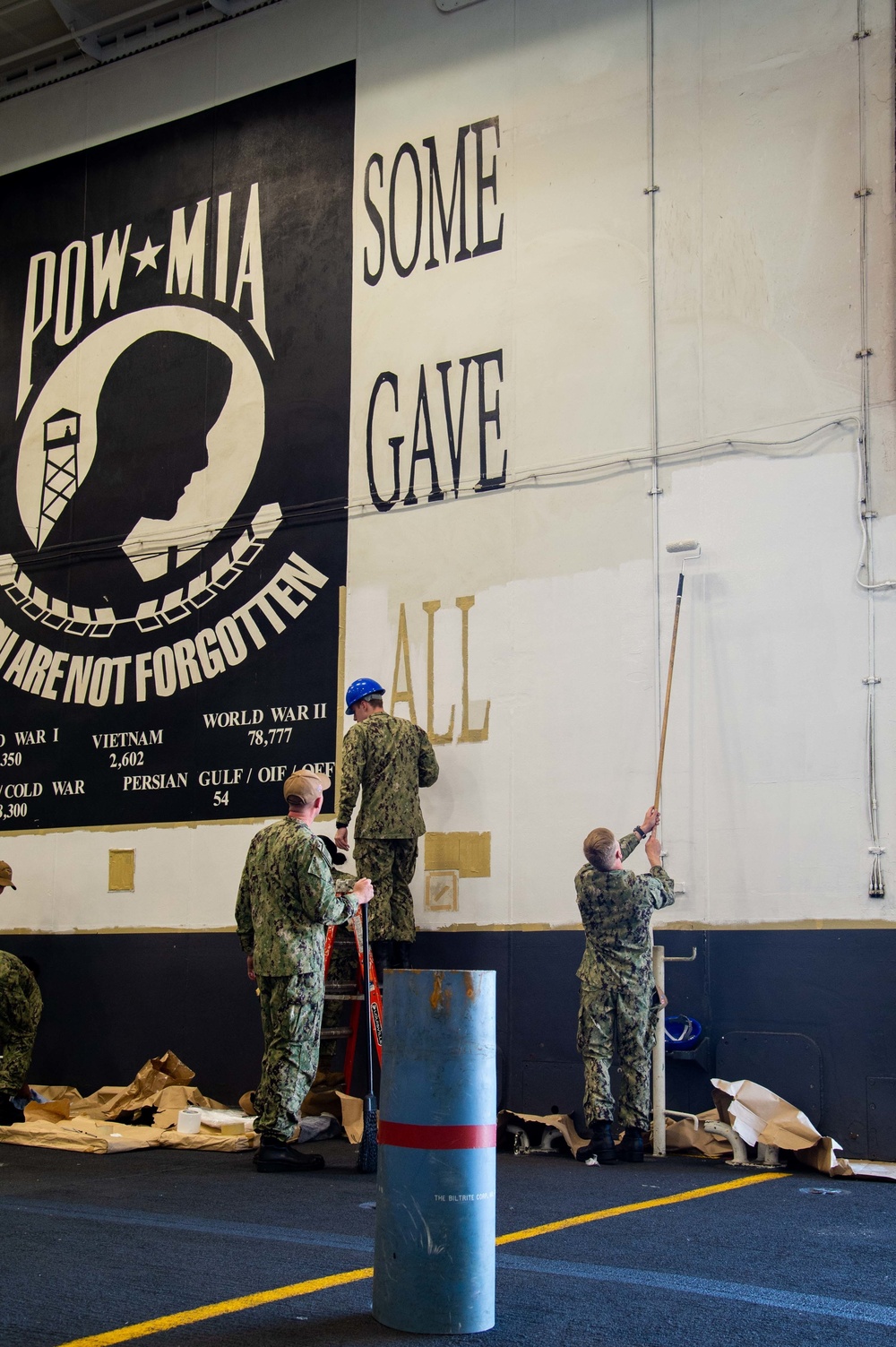 Sailors paint bulkheads in the hangar bay aboard of Nimitz-class aircraft carrier USS Carl Vinson