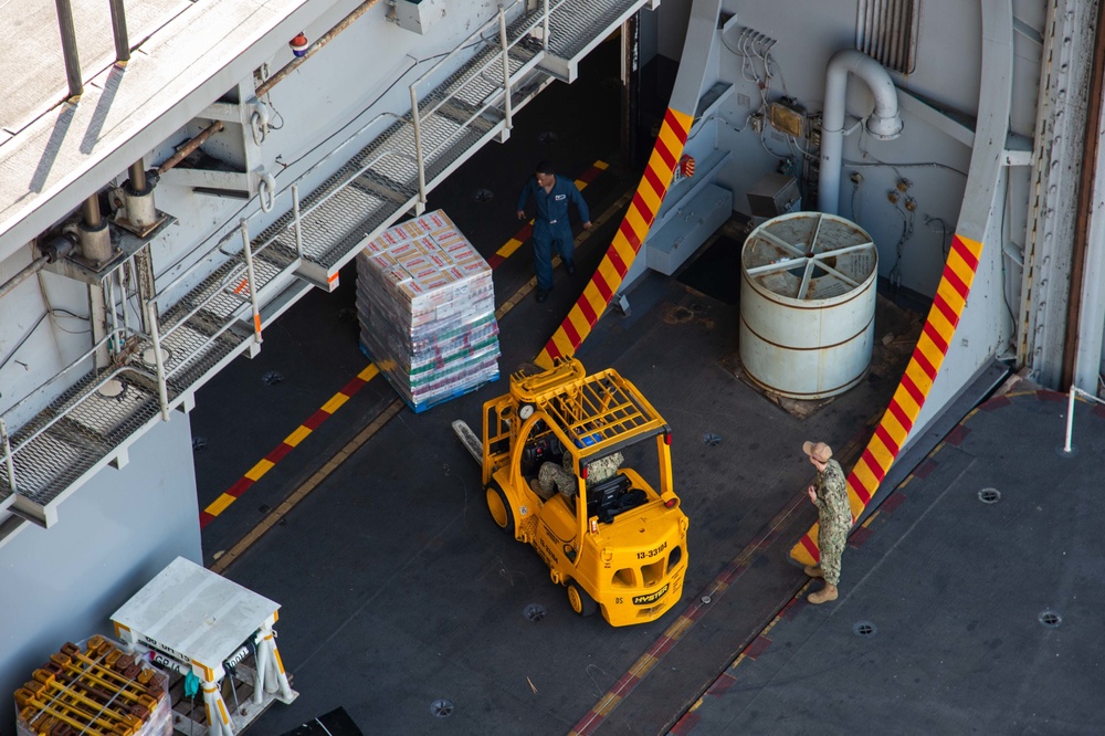 Sailors transport supplies into the hangar bay of Nimitz-class aircraft carrier USS Carl Vinson