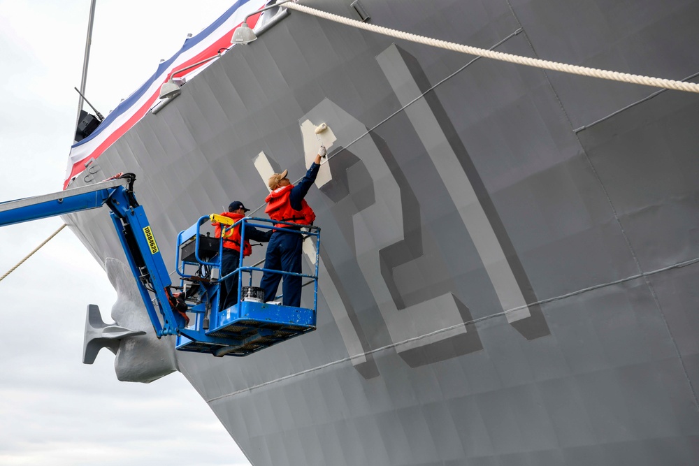 Sailors Paint the Hull Number of the USS Frank E. Petersen for Her Commissioning