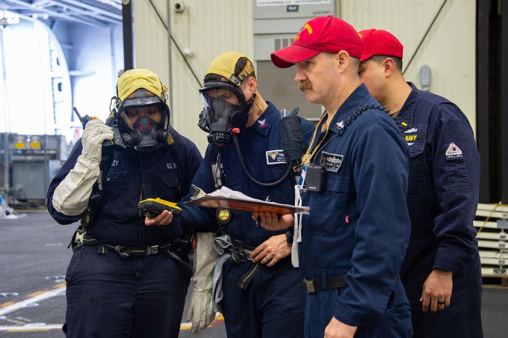 Sailors participate in damage control drills in the hangar bay aboard Nimitz-class aircraft carrier USS Carl Vinson