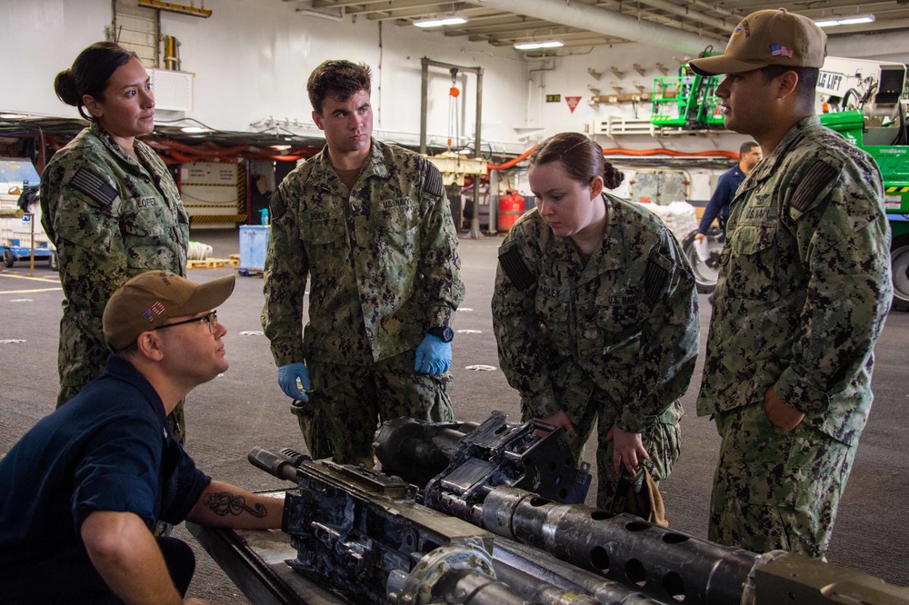 Sailors conduct maintenance on a MK 38 25mm cannon aboard Nimitz-class aircraft carrier USS Carl Vinson