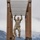 Ivy Week 2022 Mabry Mile: Monkey Bar A soldier in full camouflage uniform is traversing a horizontal ladder obstacle (monkey bars) on a military obstacle course. The structure is made of heavy timber with metal rungs, set against a backdrop of snow-capped mountains and an overcast sky. The setting appears to be a high-altitude military installation, likely in the Rocky Mountain region.