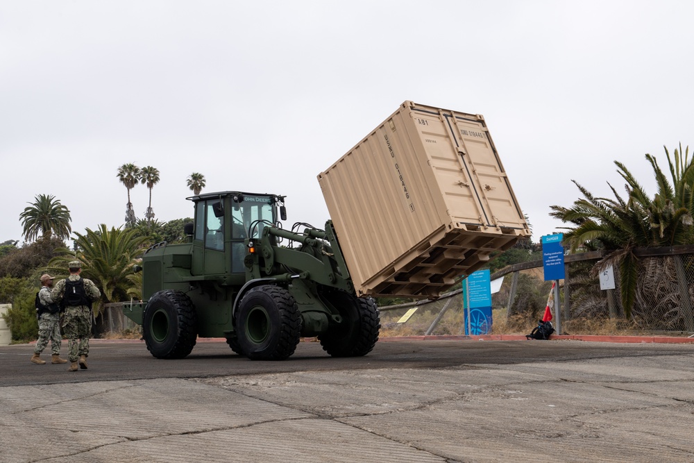 A tram moves conex boxes off of a Landing Craft Utility