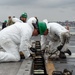 Civilian personnel conduct maintenance on a jet blast deflect the flight deck of USS Carl Vinson (CVN70)