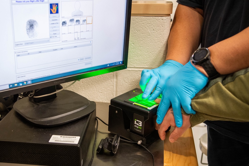 An ICE deportation officer takes the fingerprints of a detained individual