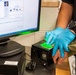 An ICE deportation officer takes the fingerprints of a detained individual