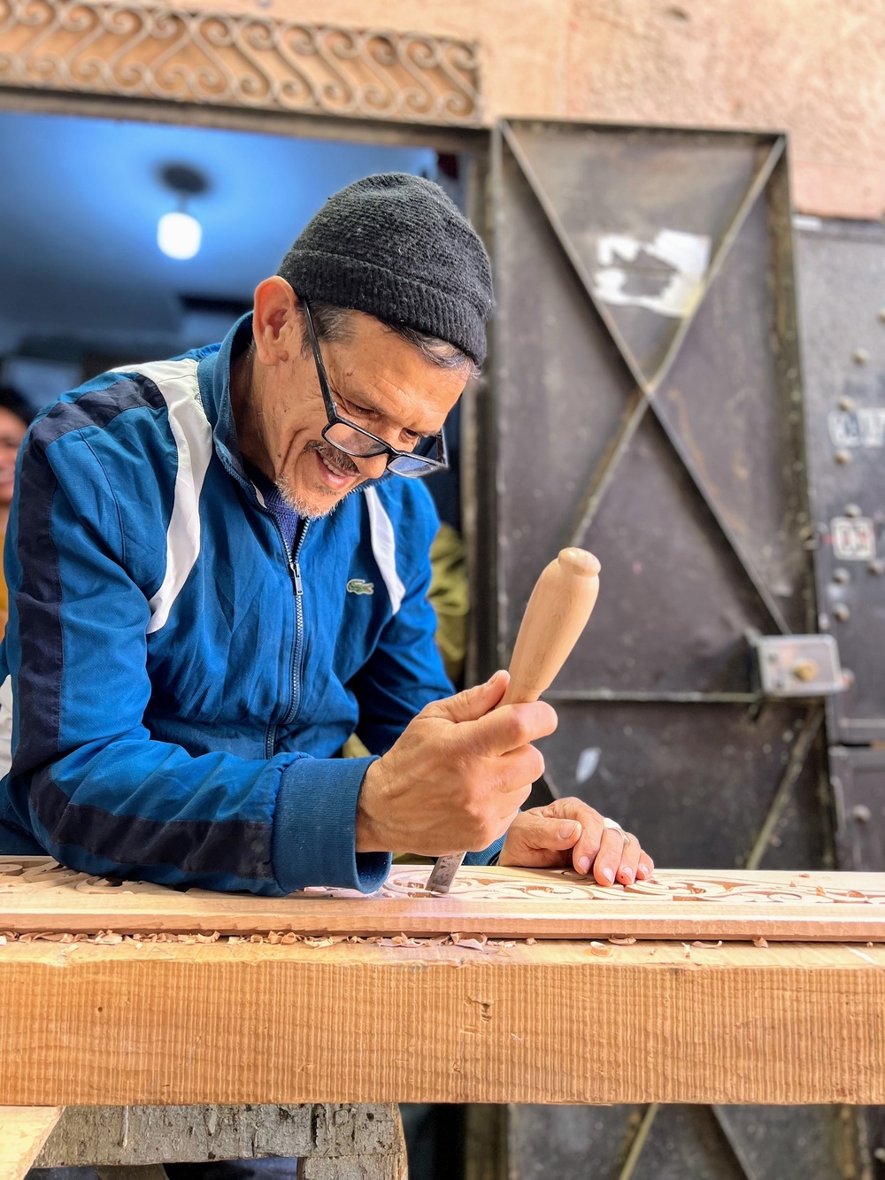 Abderrahim Assim carves design outside woodworking cooperative shop in Morocco