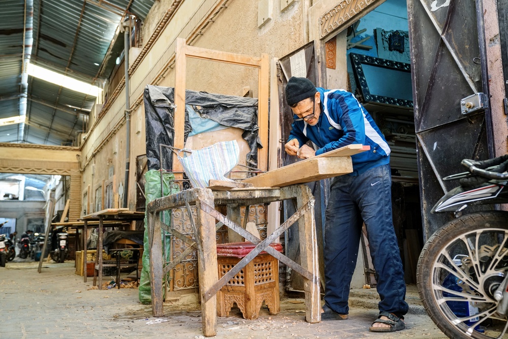 Abderrahim Assim carves design outside woodworking cooperative shop in Marrakech, Morocco