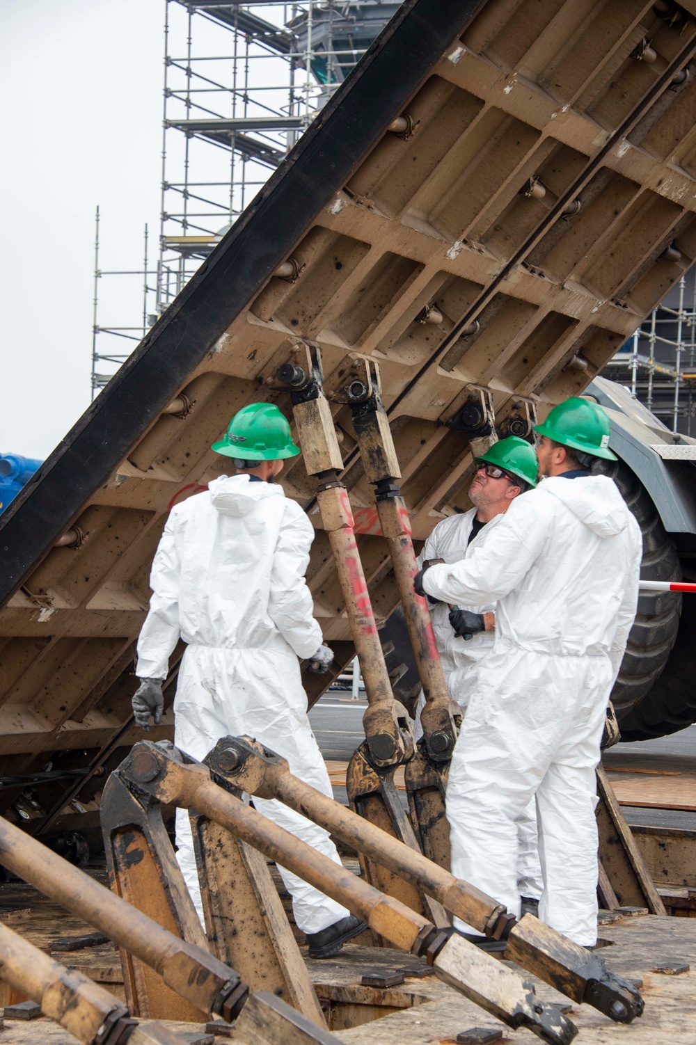 Civilian personnel conduct maintenance on a jet blast deflect on the flight deck of Nimitz-class aircraft carrier USS Carl Vinson