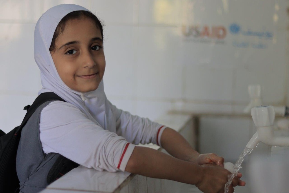 Girl washes her hands in school bathroom rehabilitated with USAID funding in Yemen