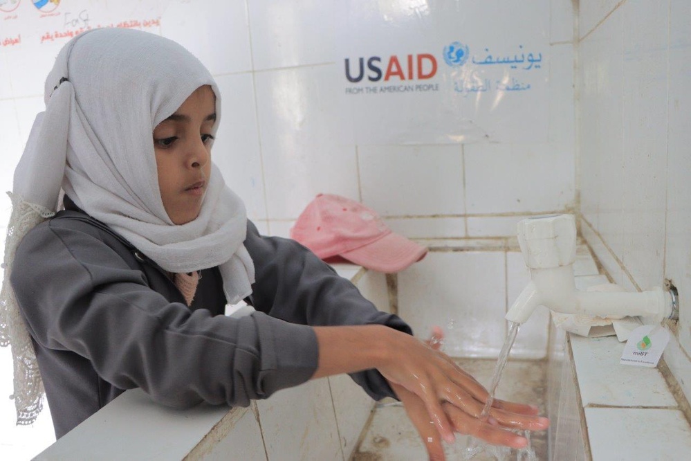 Girl washes her hands in school bathroom rehabilitated with USAID funding in Yemen