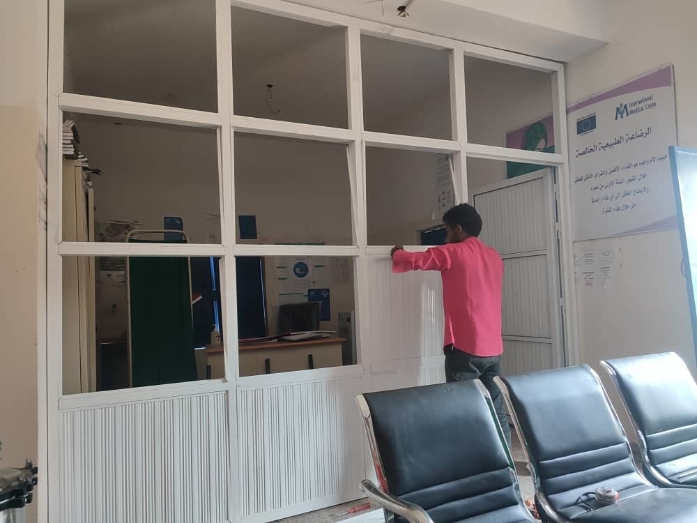 Worker installs aluminum partitions to provide privacy for reproductive health rooms at Makhran Health Center in Yemen