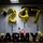 247th Army birthday cake cutting ceremony The image depicts a celebratory display for the U.S. Army's 247th birthday, featuring large gold foil number balloons spelling '247' against a tiled wall. A decorated cake with '247' candles sits on a table in front of large black letters spelling 'ARMY', surrounded by gold glitter tablecloth and floral arrangements. The color scheme is consistent with Army branding: black, gold, and white.
