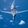 An aerial photograph taken from above showing a swept-wing strategic bomber aircraft in flight over open ocean. The aircraft is deploying flares from its rear section, visible as bright burning projectiles with smoke trails. The image is captured from a chase aircraft or tanker flying above and slightly behind the subject aircraft.