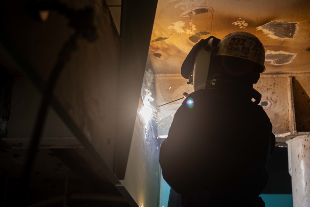 Contractor welds overhead aboard the USS John C. Stennis