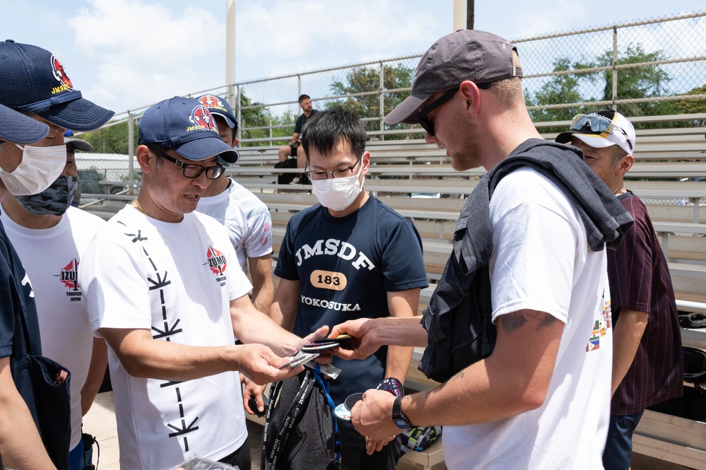 A USS Sampson Sailor and a JS Izumo Sailors exchange patches after a softball game during RIMPAC 2022