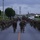 Headquarters Battalion Conditioning Hike A large formation of military personnel in camouflage uniforms conducting a road march along a base road. The troops are carrying rucksacks and wearing combat gear, moving in a column formation down a two-lane road. The setting appears to be a U.S. military installation, likely in the Pacific region based on architectural and environmental cues.