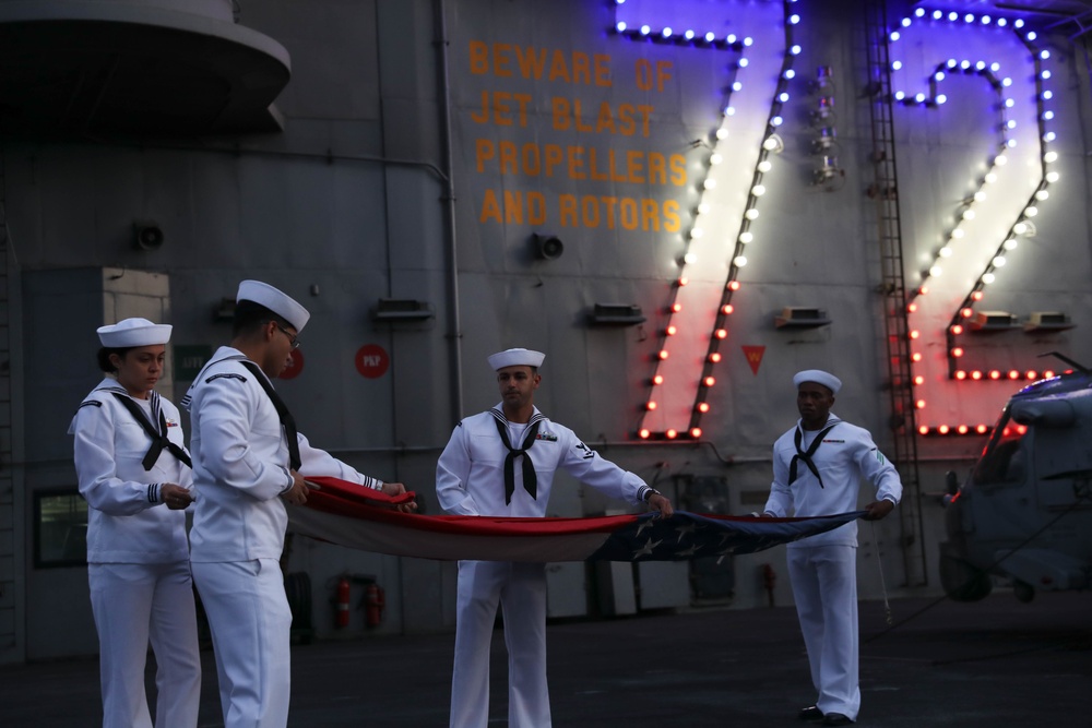 Sailors from Abraham Lincoln lower the national ensign during RIMPAC 2022