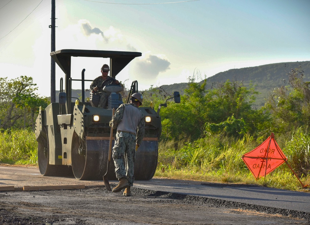 NMCB THREE Seabees operate a double-drum roller to compact the newly-placed asphalt pavement.