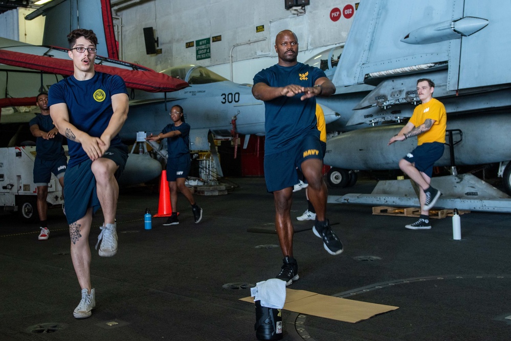 USS Ronald Reagan (CVN-76) Sailors preform physical fitness hangar bay