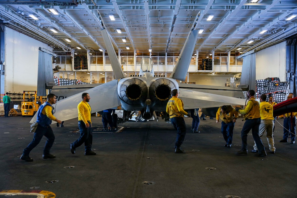 Abraham Lincoln Sailors transport aircraft in the hangar bay