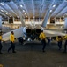 Abraham Lincoln Sailors transport aircraft in the hangar bay