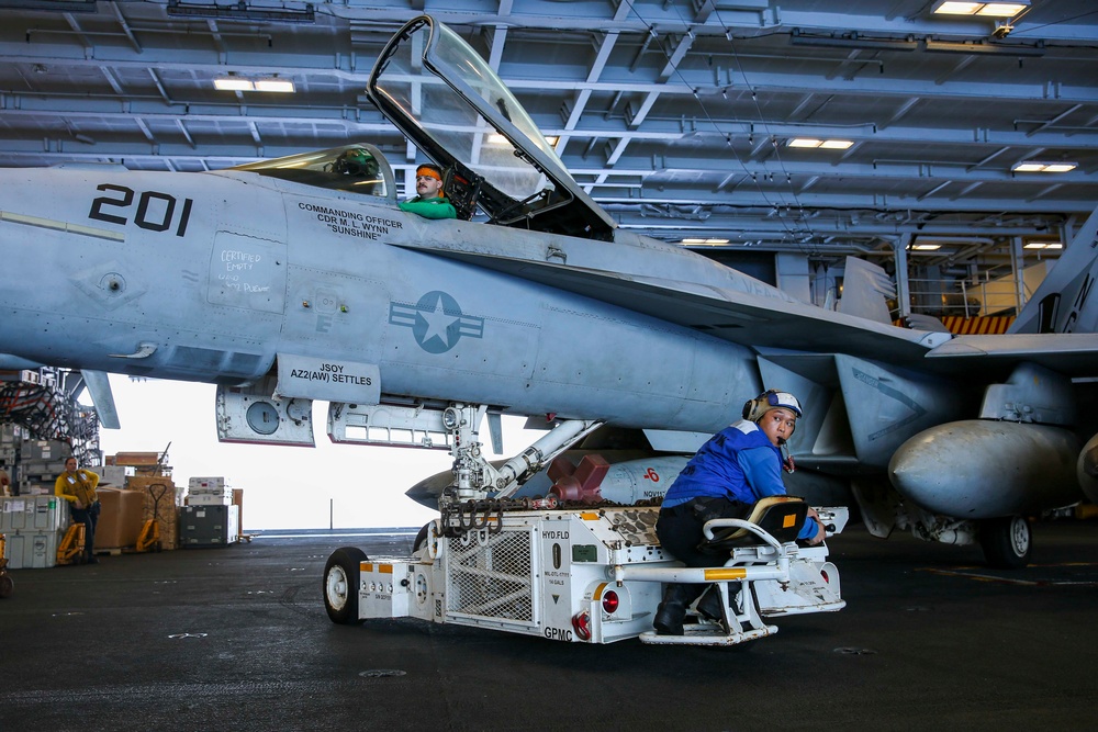 Abraham Lincoln Sailors transport aircraft in the hangar bay